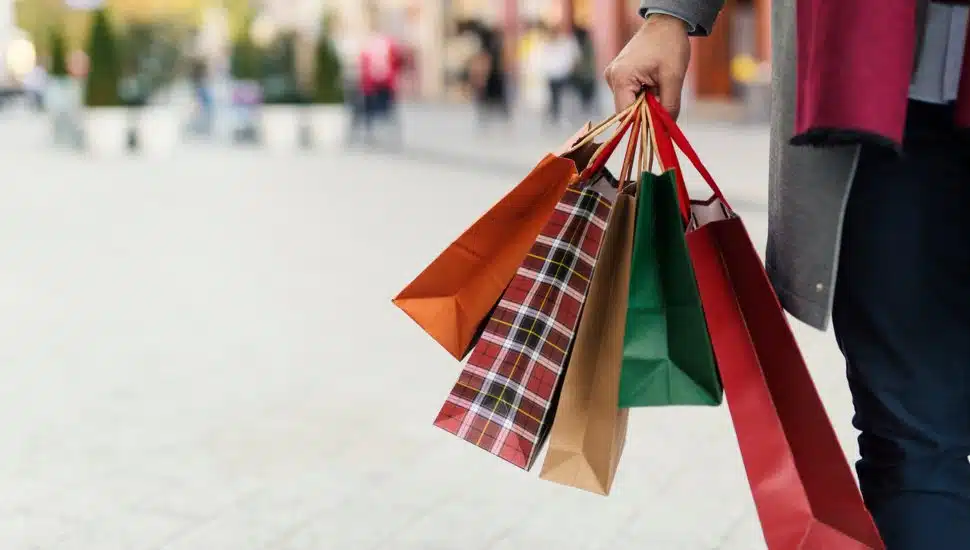 Man holding shopping bags with presents on the street.