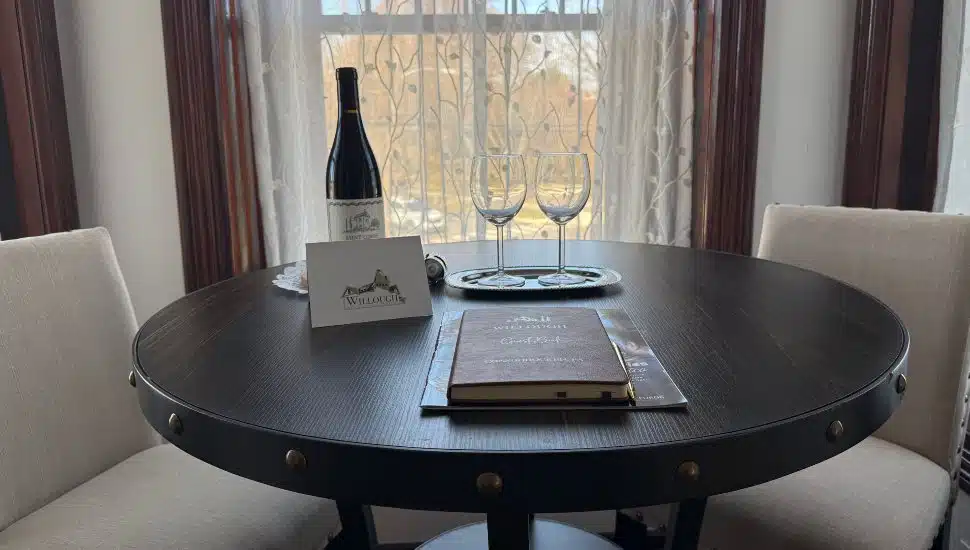 A bottle of wine sits on a table with wine glasses in a private room at The Willough Bed + Breakfast.