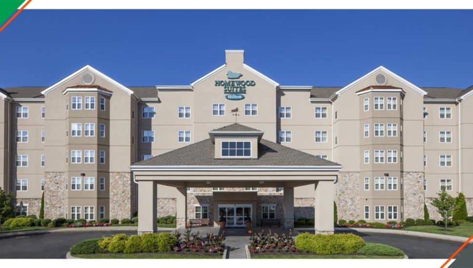 Exterior view of the Homewood Suites by Hilton in Valley Forge, showcasing the hotel’s main entrance, landscaped grounds, and multi-story facade under a clear blue sky.