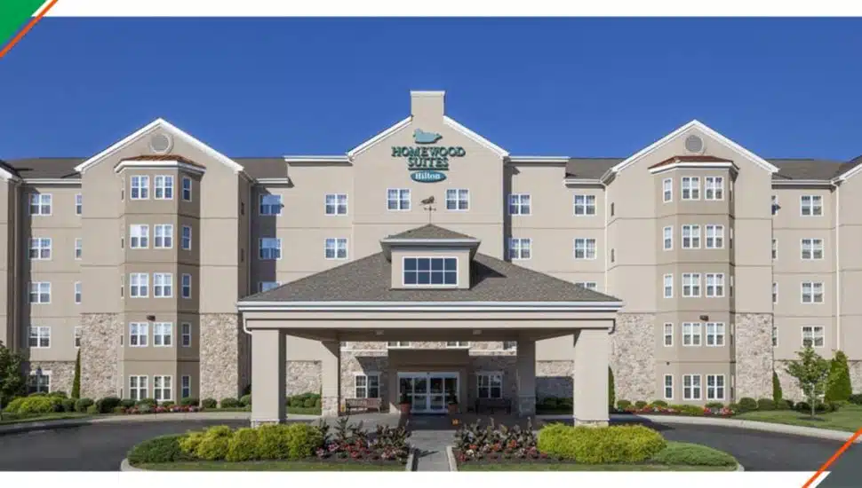 Exterior view of the Homewood Suites by Hilton in Valley Forge, showcasing the hotel’s main entrance, landscaped grounds, and multi-story facade under a clear blue sky.