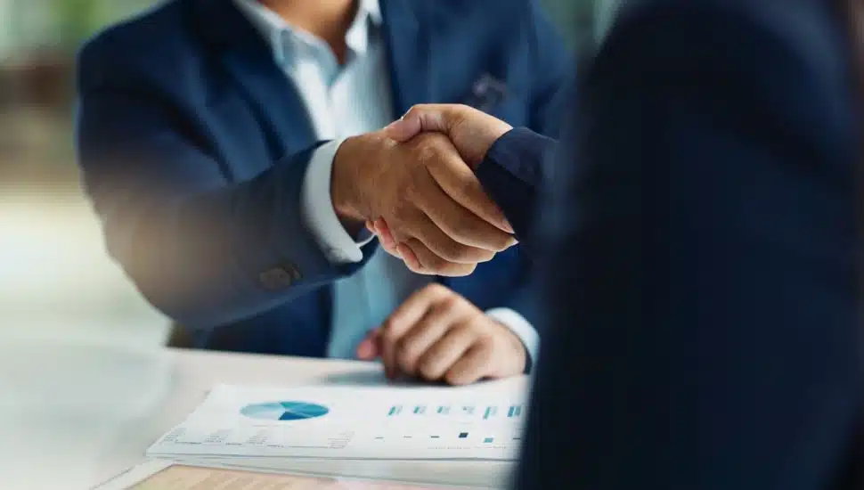 Two business people shake hands over an acquisition.