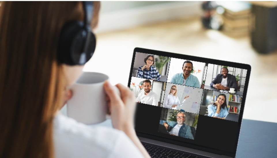 A woman drinks coffee and chats on her laptop with people online.