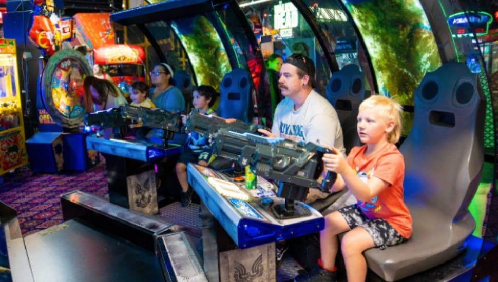 A family plays an arcade game together at Arnold's Family Fun Center.