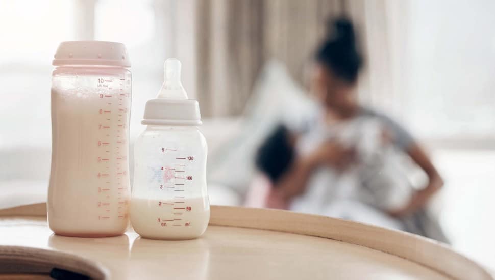 Defocused shot of a young mother bottle feeding her daughter on the sofa