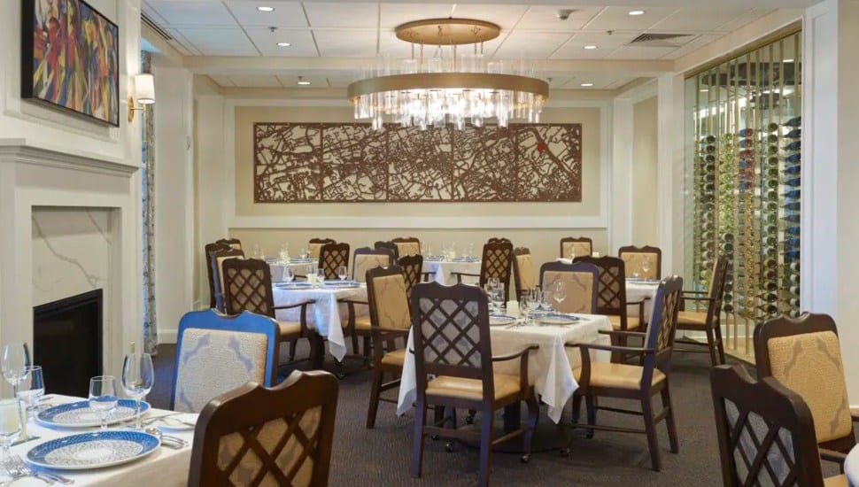 A painting of the Main Line hangs over a set table at the Carlton Commons in Gladwyne's Waverly Heights.
