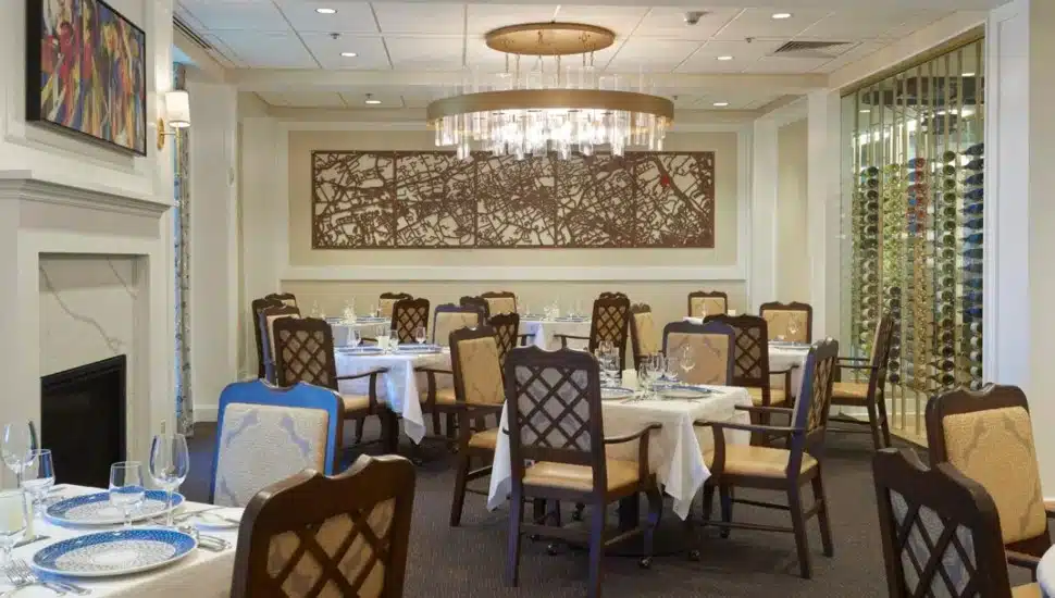 A painting of the Main Line hangs over a set table at the Carlton Commons in Gladwyne's Waverly Heights.