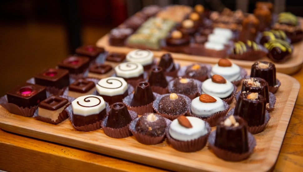 A colorful array of artisan chocolates is elegantly presented on a stylish plate during a joyful confectionery event. Each piece is crafted with unique flavors and artistic designs.