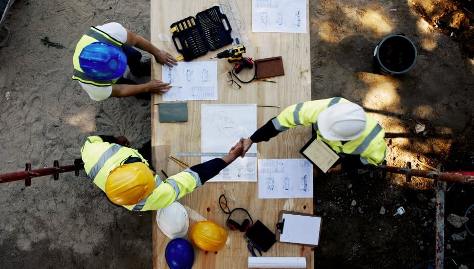 General contractors shake hands over blueprints.