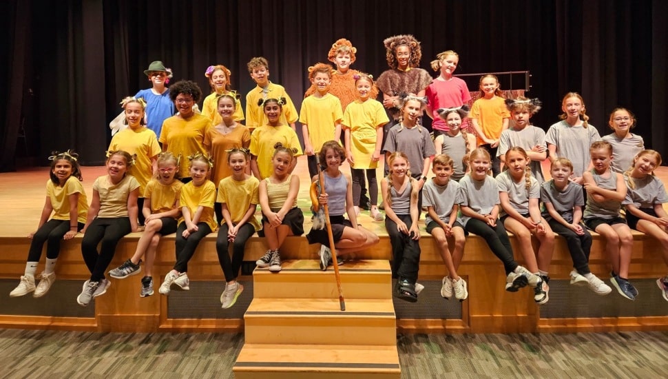 Group of student actors pose for picture on auditorium stage.