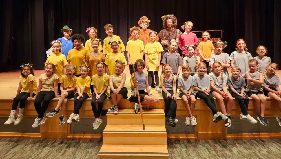 Group of student actors pose for picture on auditorium stage.