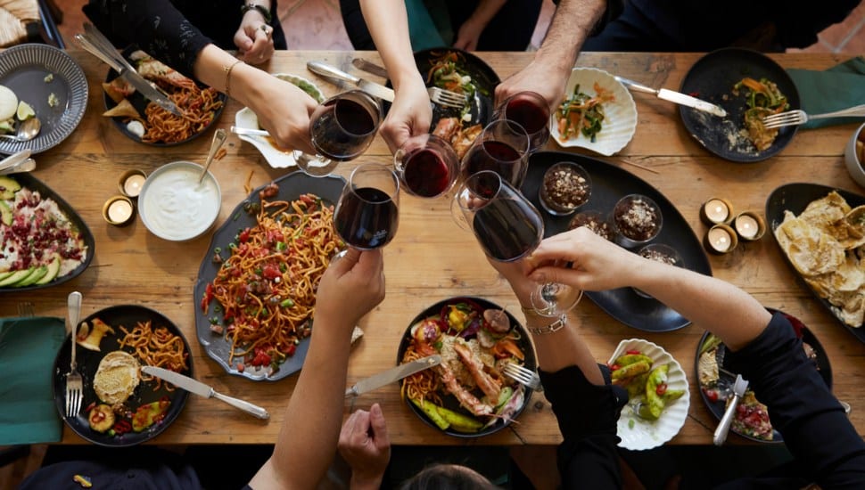 Friends cheers their wine glasses at a restaurant dining table.