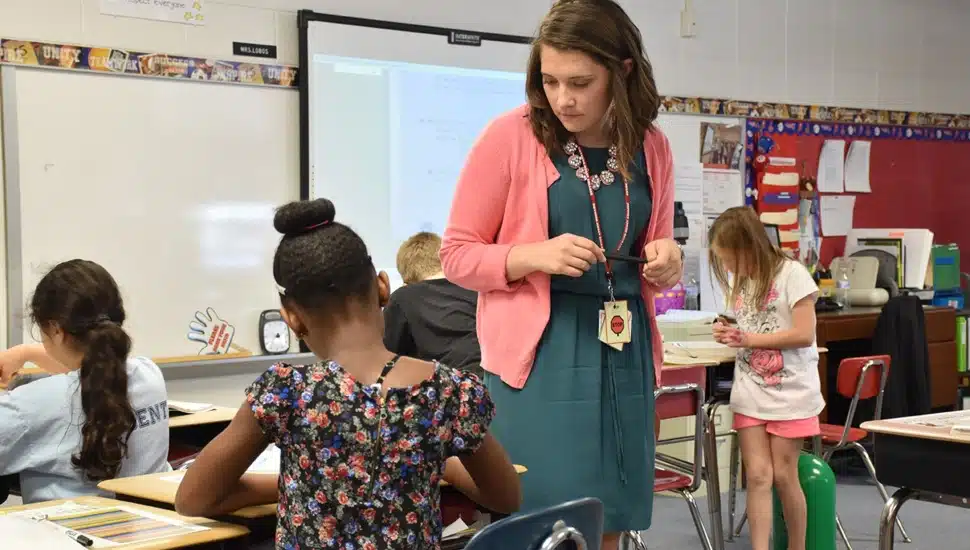 Elementary school teacher helps students in classroom.