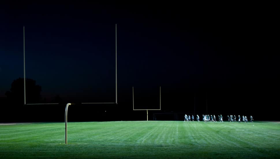Football players running on the field at night