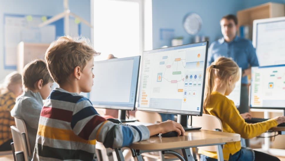 Kids on computers in classroom.