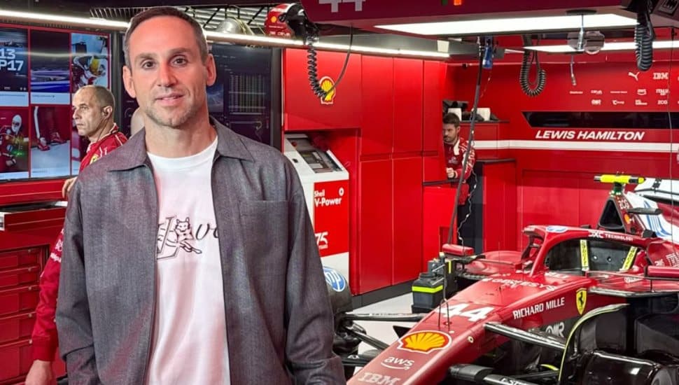 Michael Rubin stands in a garage with a Formula 1 car in the background.