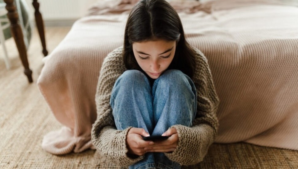 Teenage girl scrolls through her cell phone.