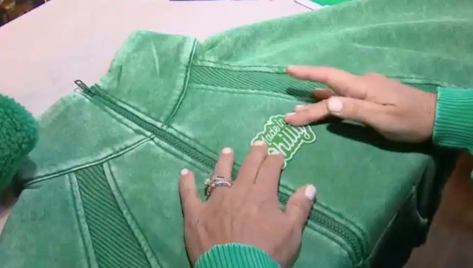 Primitive Boutique owner Ann Martinelli places a 'Made in Philly' patch on a green sweater.