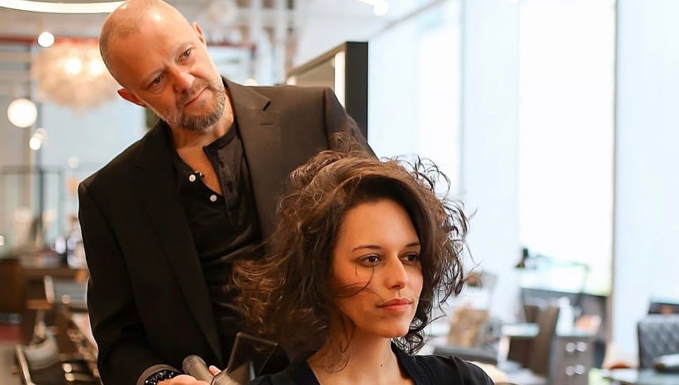 Artur Kirsh styles a woman's hair.