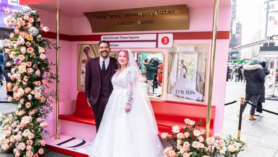 A couple clad in wedding attire stands at a David's Bridal pop-up in Times Square.