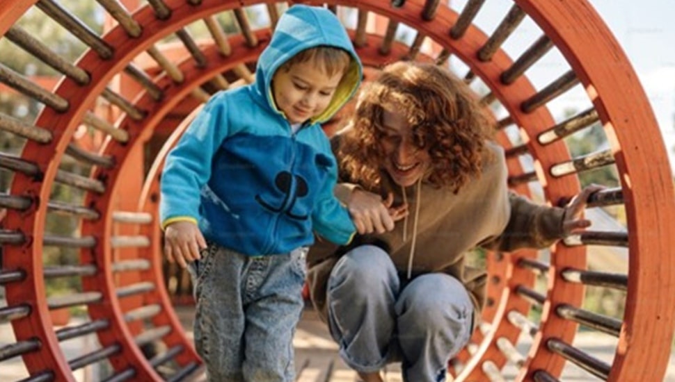 Woman and her son play on the playground.