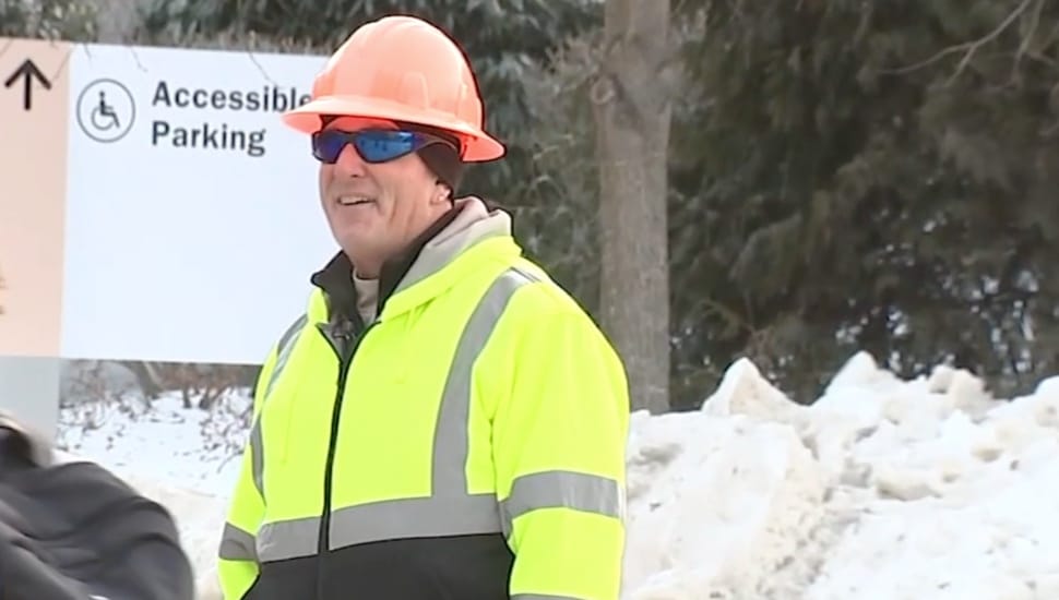Crossing guard Greg Hamell smiles as he guides pedestrians across the street.