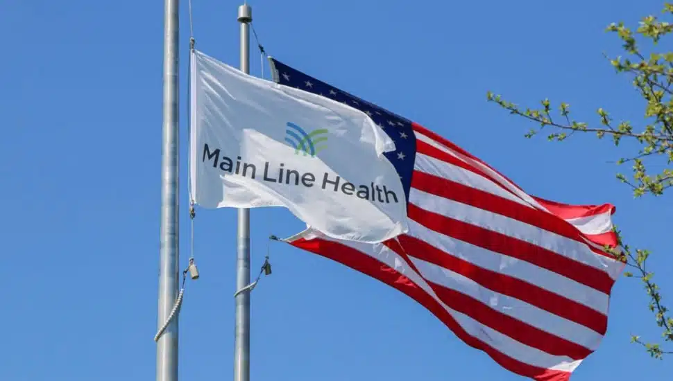 A Main Line Health flag waves in front of the American Flag.