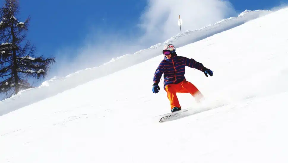 A man snowboards down a snowy hill.