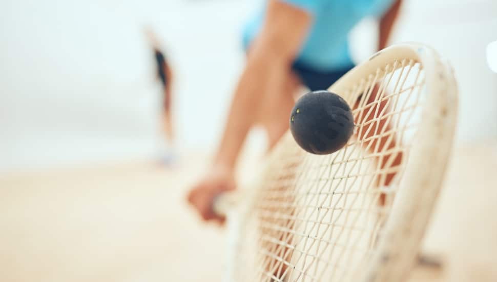 A squash racket smacks a ball.