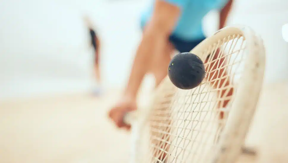 A squash racket smacks a ball.