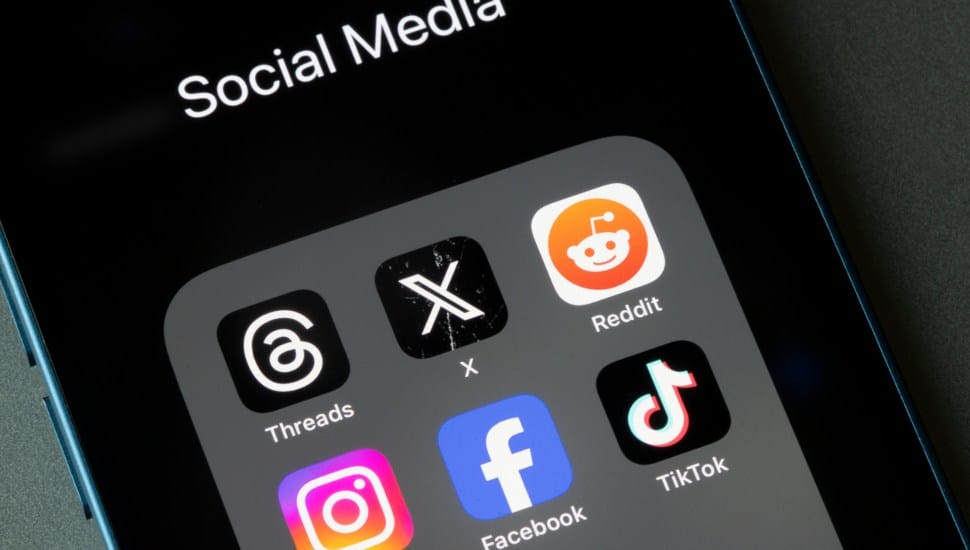 A phone displays the TikTok app along with other social media apps.