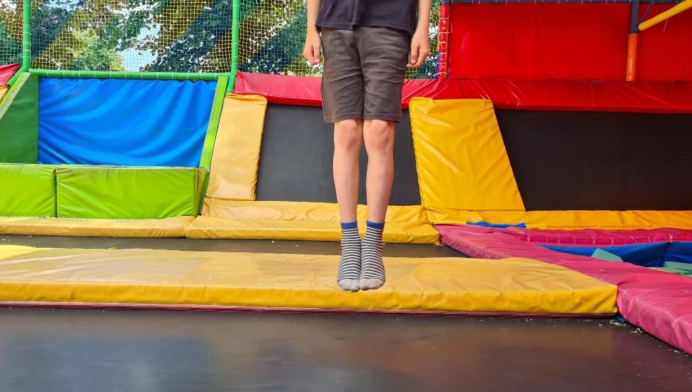 A young boy jumps on a trampoline at a park.
