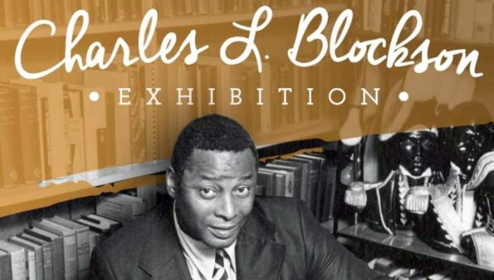 Black-and-white photograph of Charles L. Blockson surrounded by books and cultural artifacts, featured in a museum exhibition.