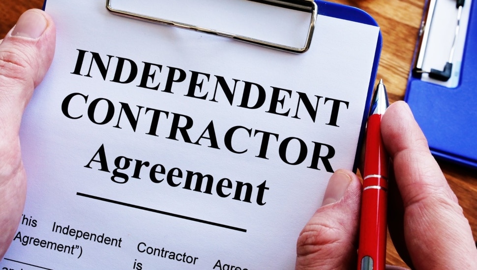 Man is signing Independent contractor agreement by pen.