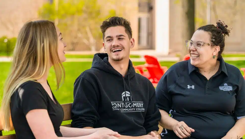 MCCC students sitting on campus bench and talking/smiling.