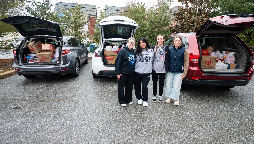 West Chester University students stand with vehicles filled with donated food items collected during the CBPM “Soup-er” Bowl Food Drive for the University Resource Pantry.