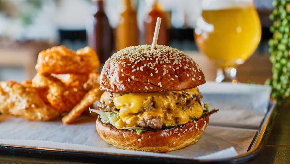 A burger on a plate with onion rings.