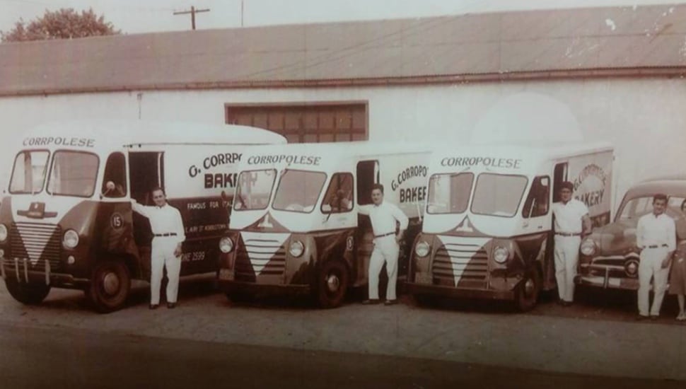 An old black and white photo of three Corropolese delivery drivers standing by their trucks.