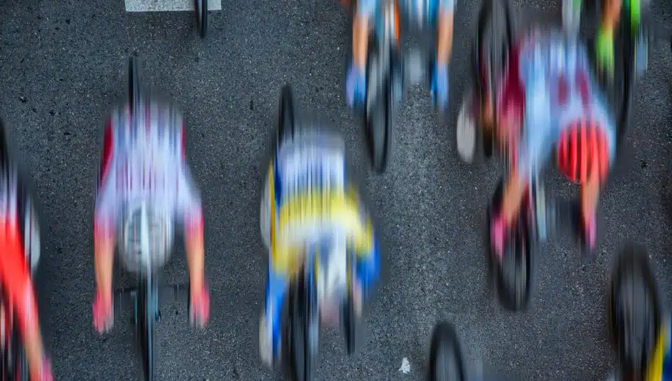 Blurred image of cyclists riding at full speed on an asphalt road.