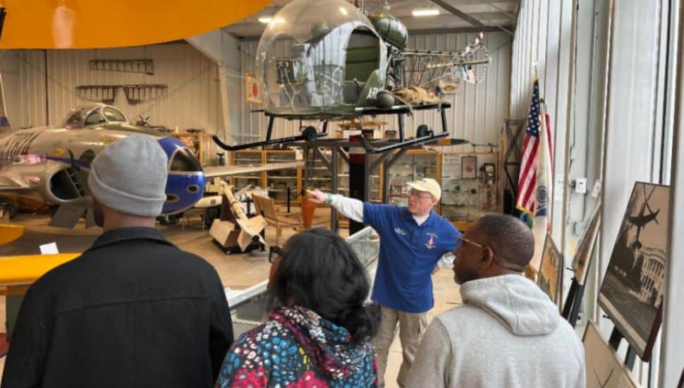 A docent leads visitors on a guided tour through the Wings of Freedom Aviation Museum, sharing stories behind historic aircraft and artifacts.