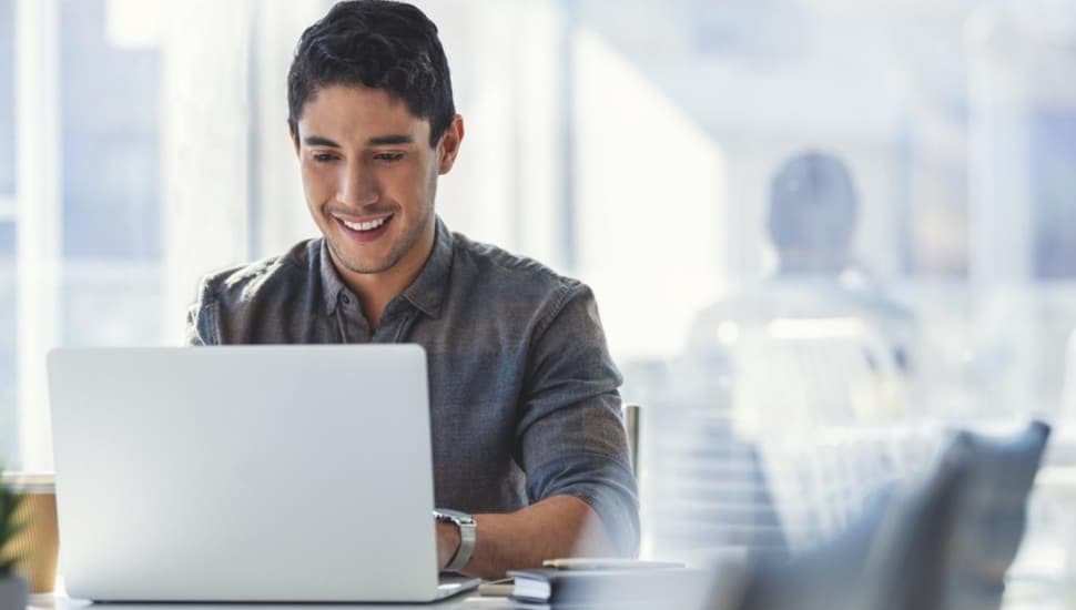 Young man works on laptop computer.