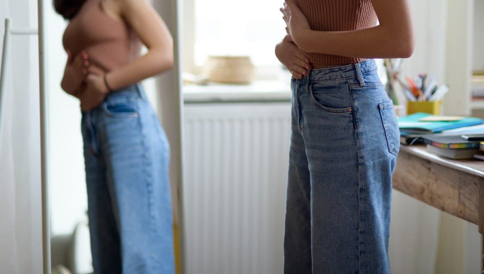 Young teenage girl looking in the mirror in the room.