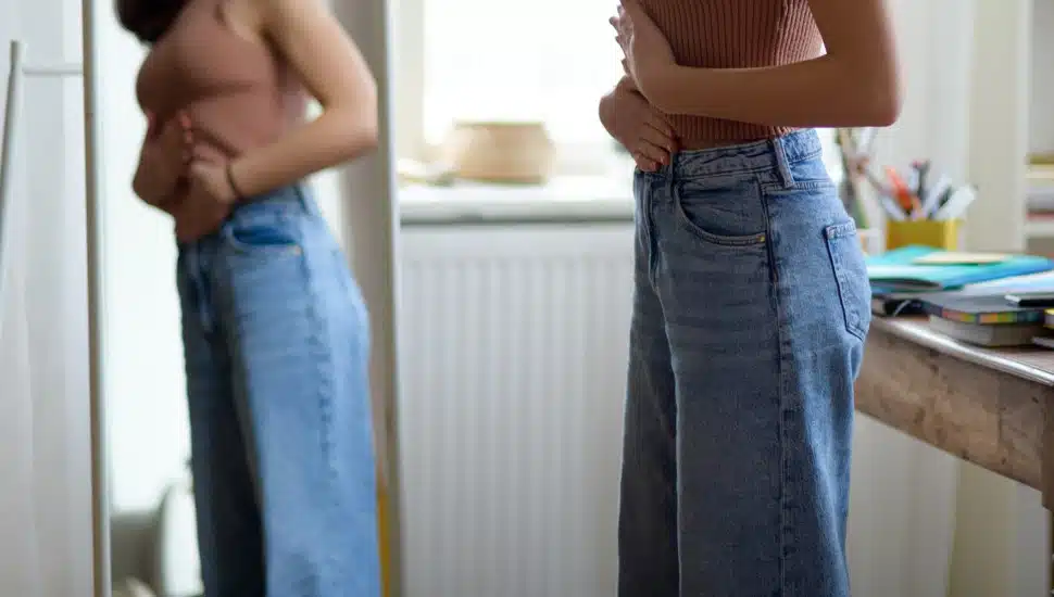 Young teenage girl looking in the mirror in the room.