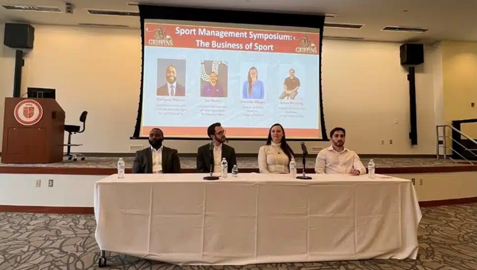 Four panelists sit at table for symposium.