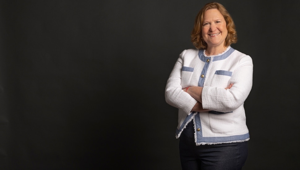 Female business executive stands with arms folded.