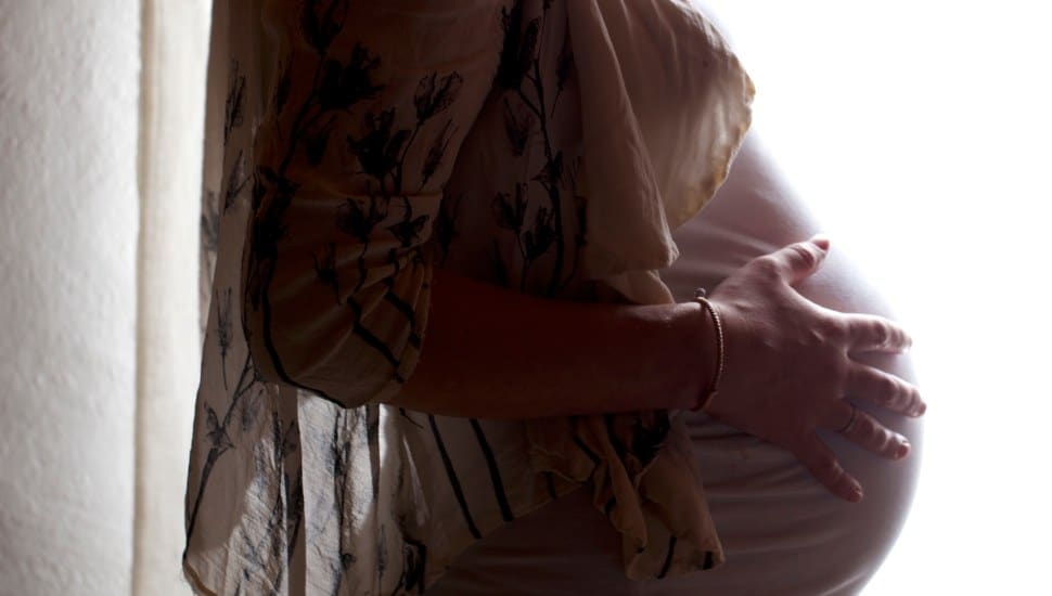 A pregnant woman holds her baby bump.