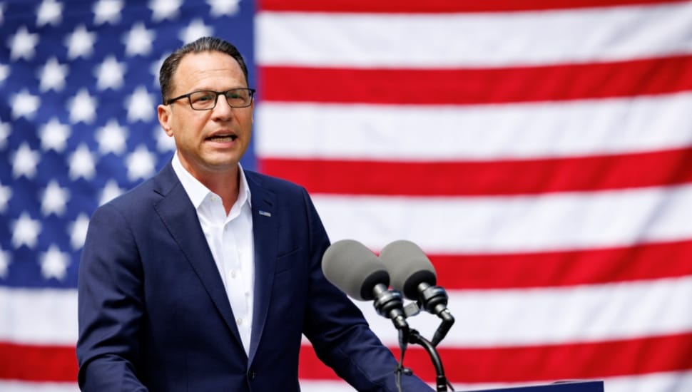 Josh Shapiro speaks from a podium in front of an American flag.