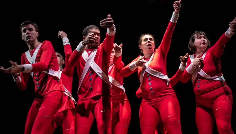 Actors in red Revolutionary War-inspired costumes perform a scene from The American Revolution stage production.