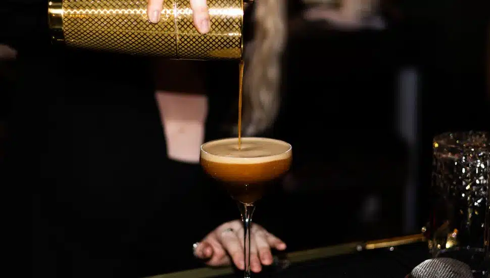 Perfectly Crafted Espresso Martini - Expert Mixology. close up image of drink being poured at bar.