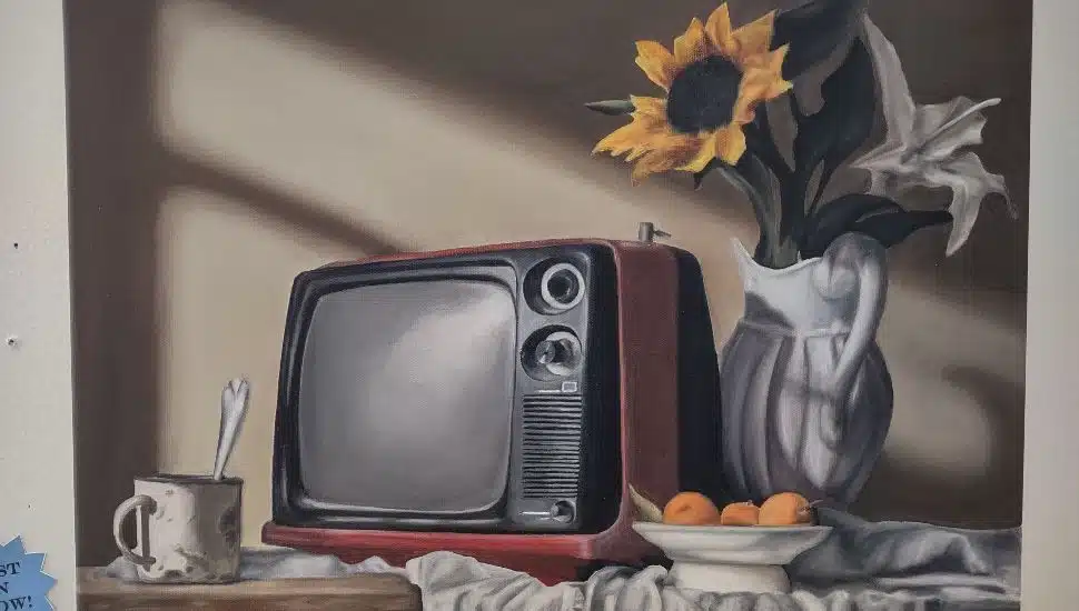 Still life painting of a vintage red television, sunflowers in a vase, fruit bowl and mug displayed at Montgomery County Community College’s Blue Bell Student Art Exhibition.
