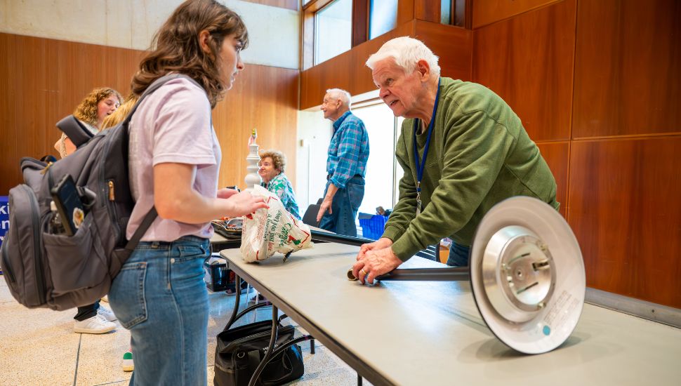 Student speaks with a volunteer at a sustainability table during a zero waste event.